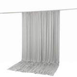 Light gray curtain draped on a rod with pooled fabric on the floor
