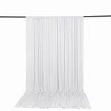 White sheer curtain panel hanging on a rod with pooled fabric on the floor