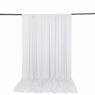 White sheer curtain panel hanging on a rod with pooled fabric on the floor