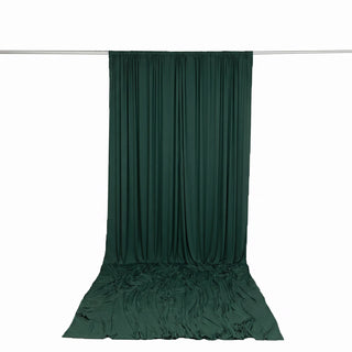 Dark green draped fabric curtain on a rod against a white background