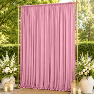 Pink draped wedding backdrop with gold stand and floral arrangements
