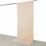 Beige sheer backdrop curtain hanging from a black rod on a white wall