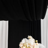 Floral arrangement with feathers against a black and white backdrop.