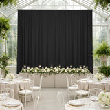 Elegant black drapery backdrop for a wedding reception with floral arrangements.
