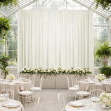 Elegant wedding reception setup with floral arrangements and draped curtains.