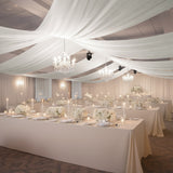 Elegant wedding reception setup with floral centerpieces and soft drapery.