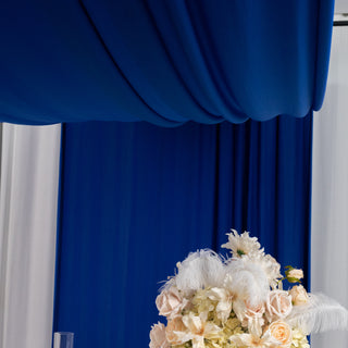 Elegant floral arrangement with feathers against a blue draped backdrop.