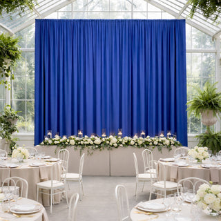 Elegant wedding reception setup with blue curtain backdrop and floral table decor.