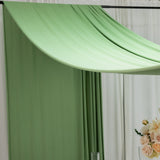 Green draped fabric backdrop with floral arrangement.