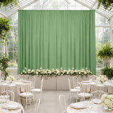 Elegant wedding reception setup with green backdrop and floral arrangements.