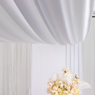 Elegant floral arrangement with soft white drapery backdrop.