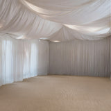 Elegant draped fabric ceiling in a spacious, softly lit room.