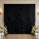 Elegant black draped wedding backdrop with white floral arrangements