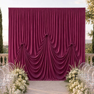Elegant burgundy draped wedding backdrop with white floral aisle decor