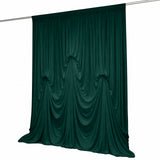 Dark green draped curtain hanging on a rod against a white background