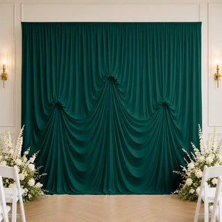 Emerald green draped wedding backdrop with floral aisle decor