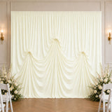 Elegant ivory wedding backdrop with draped curtain and floral arrangements