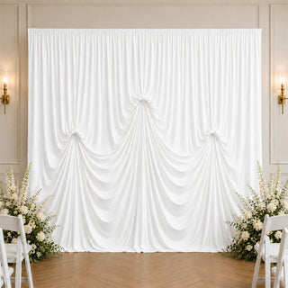 Elegant white wedding draped backdrop with floral arrangements and chairs