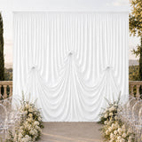 Elegant white wedding draped backdrop with floral aisle and clear chairs