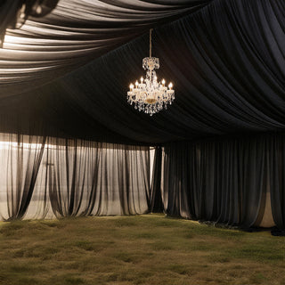 Elegant chandelier hanging in a draped black tent interior.