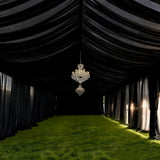 Elegant black tent interior with chandeliers and lush green grass flooring.