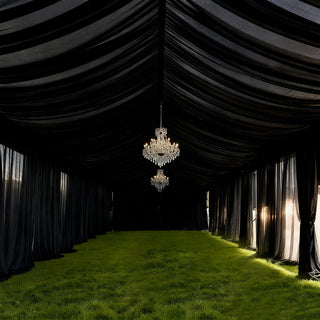 Elegant black tent interior with chandeliers and lush green grass flooring.