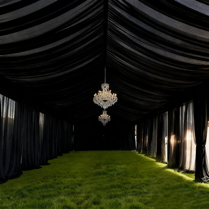 Elegant black tent interior with chandeliers and lush green grass flooring.