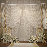Elegant pearl drapery backdrop for weddings with floral arrangements.