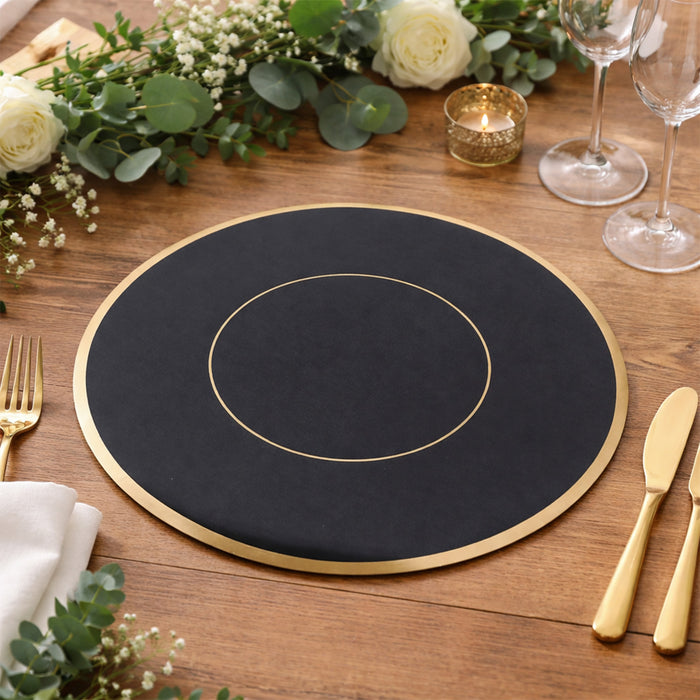 Elegant black placemat with gold rim on wooden table setting.