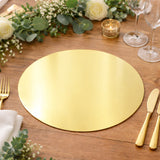 Gold round placemat on a rustic wooden table with floral decor and tableware.