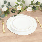 Elegant white dinnerware set with gold accents on a wooden table.
