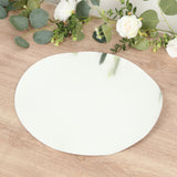 Round mirror placemat on a wooden surface with greenery and flowers.