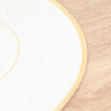 Elegant white plate with gold trim on a wooden surface.