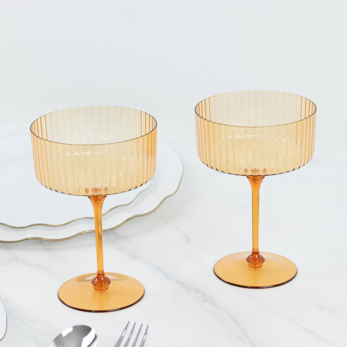 Amber ribbed stemware set on a marble table.