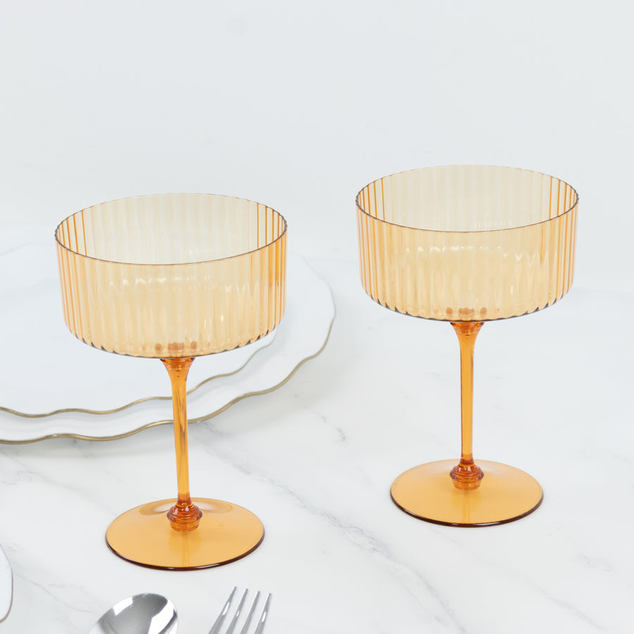 Amber ribbed stemware set on a marble table.