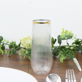 Elegant ribbed glass vase with gold rim on a wooden table with greenery.