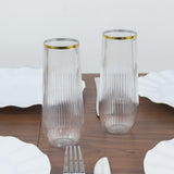 Elegant ribbed glass tumblers with gold accents on a dining table.