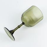 Green ribbed wine glass with a fluted design on a white background