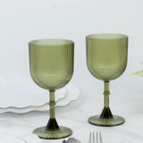 Green ribbed glassware set on white marble background.