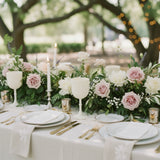 Elegant outdoor dining table adorned with floral arrangements and candles.