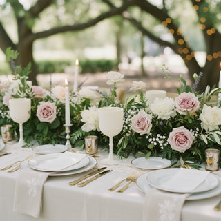 Elegant outdoor dining table adorned with floral arrangements and candles.