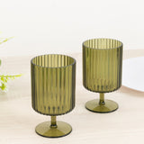 Green ribbed glass candle holders on a wooden surface.