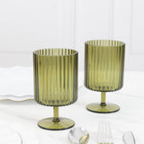Green ribbed glass goblets on a marble surface.