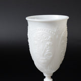 White decorative cup with intricate embossed design.