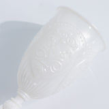 White ornate cup with embossed design on a plain white background