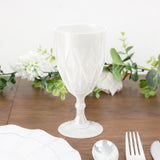 White decorative goblet on a table with greenery.