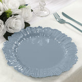 Blue scalloped edge plate on a dining table with white roses and cutlery.