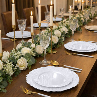 Elegant dining table set with white plates, crystal glasses, and floral decor.