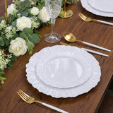 Elegant white plates set on a wooden table with gold utensils and floral decor.