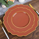 Elegant terracotta plates with gold trim stacked on a wooden table.